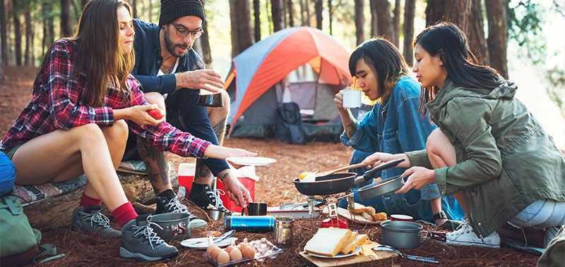 Freunde beim Camping-Frühstück im Wald