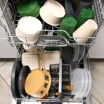 Open dishwasher filled with reusable crockery